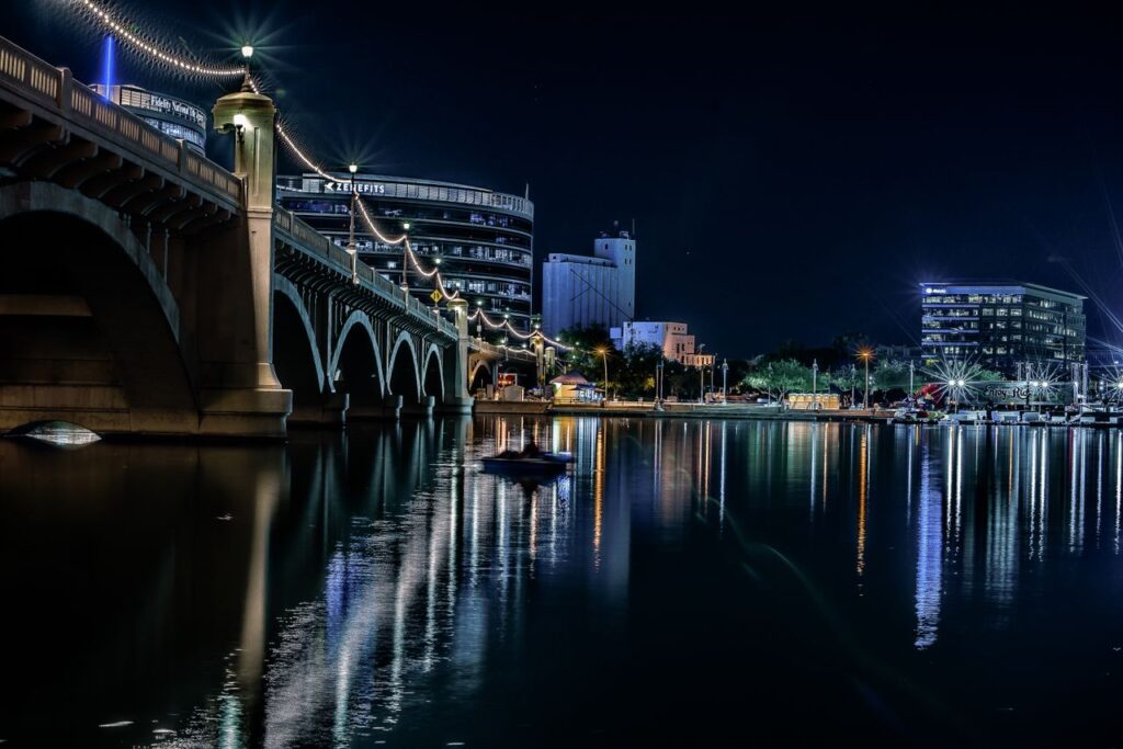 Stunning night view of Tempe, Arizona, featuring the illuminated bridge and skyline reflections on the water.